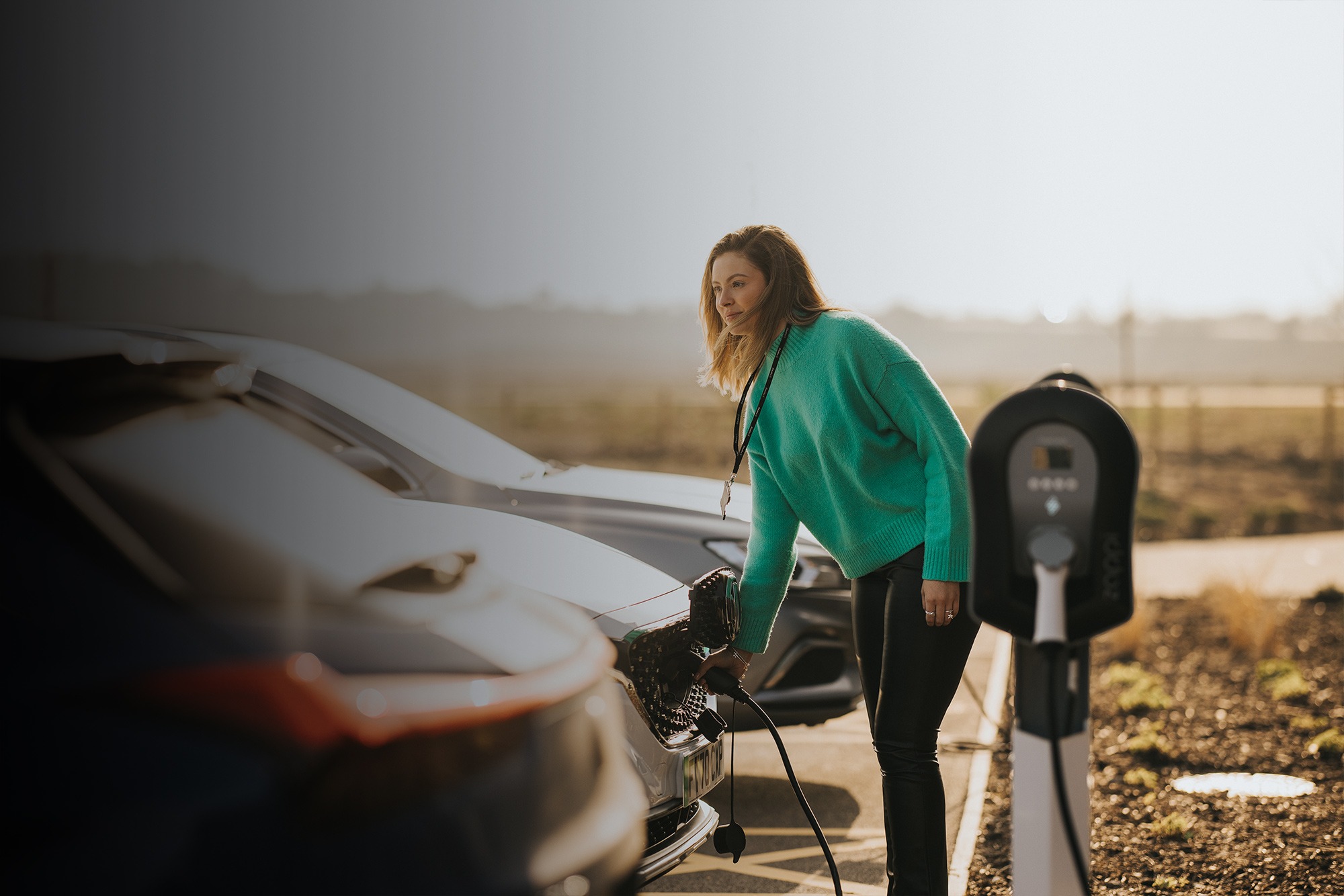 Landscape image of woman charging her EV using myenergi's Zappi EV charger
